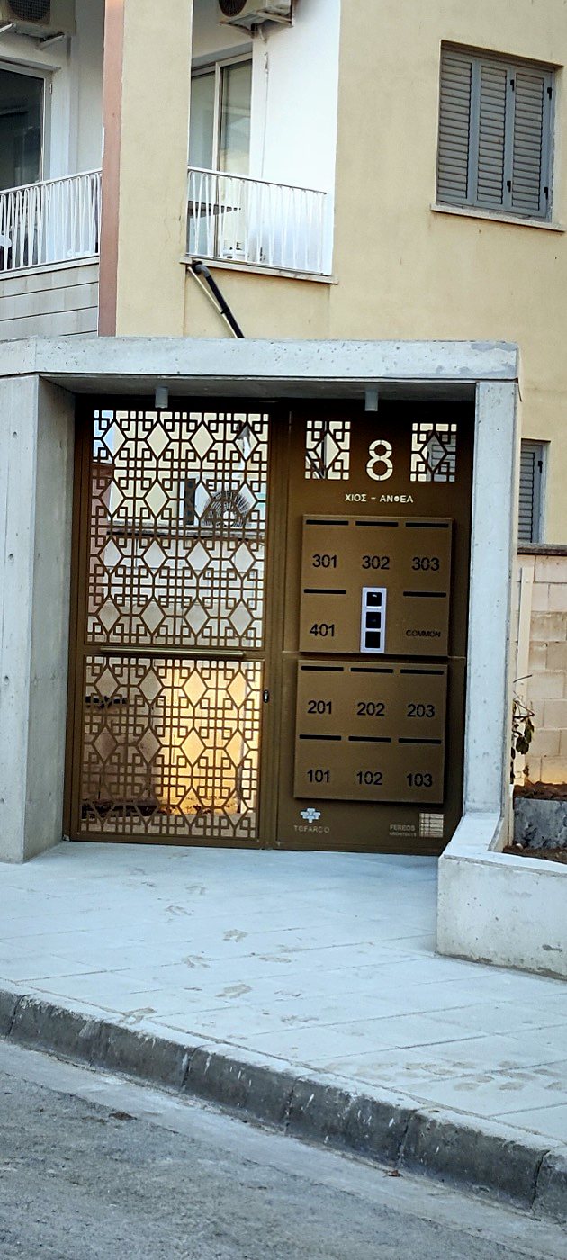 Bronze powder-coated laser-cut entrance door with integrated mailboxes