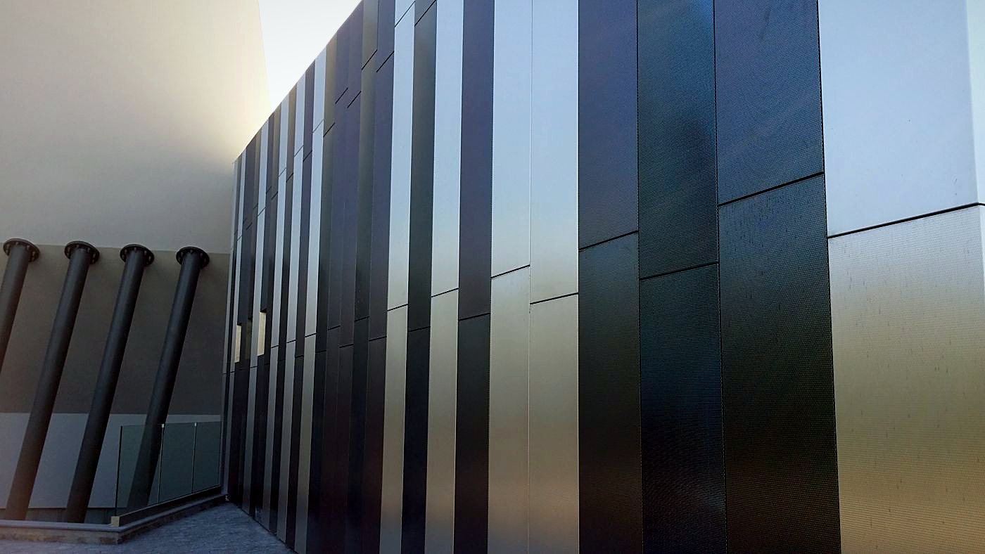 Striped metal façade cladding in alternating dark and brushed panels